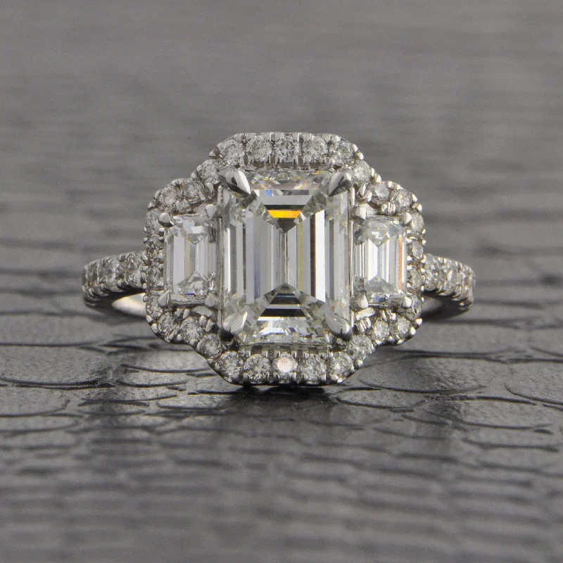 Ladies engagement rings floral diamond-Magnificent Three Stone Emerald Cut Halo Engagement Ring in White Gold